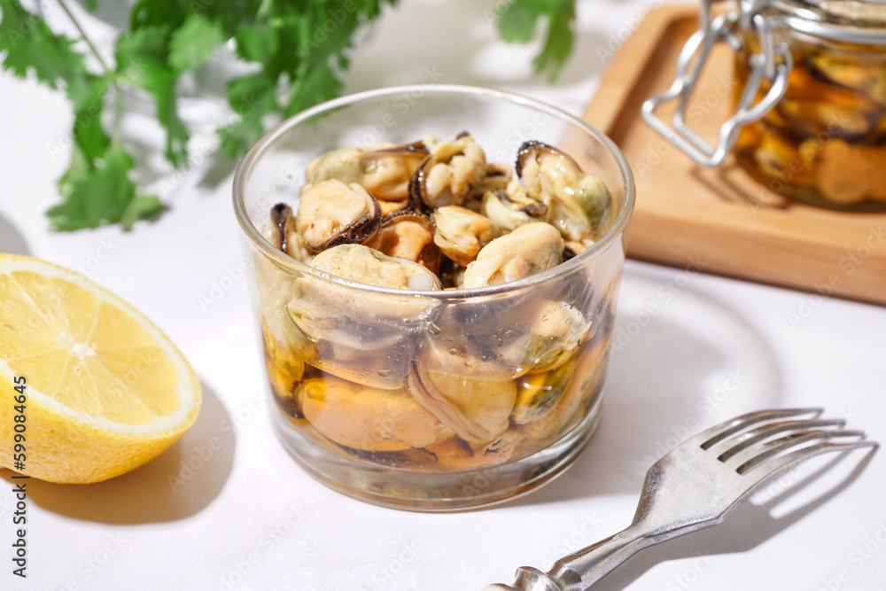 Glass bowl of pickled mussels on white background