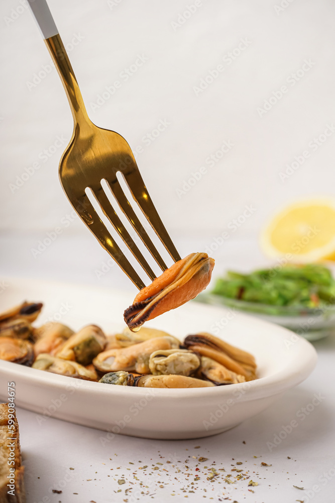 Plate with pickled mussels and bowl of seaweed salad on white background