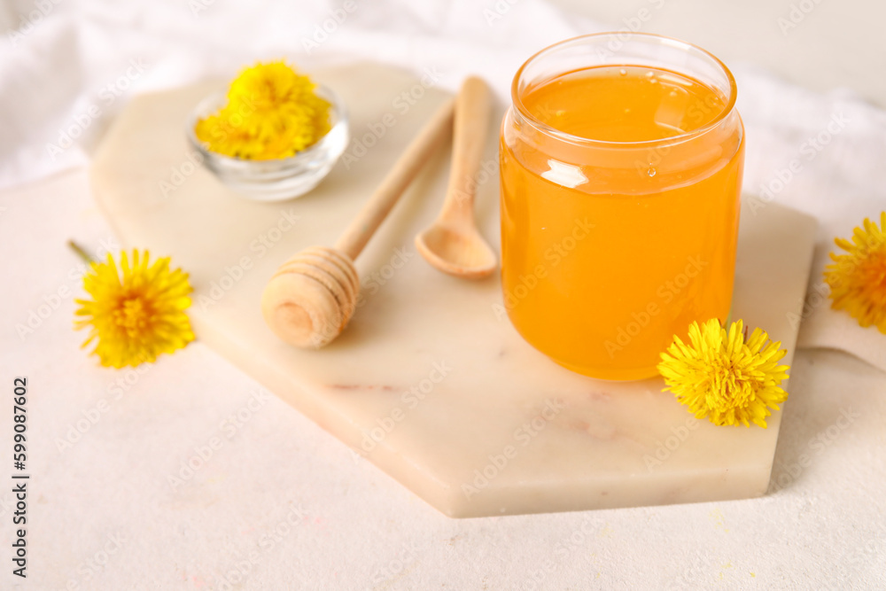 Board with jar of dandelion honey on white table