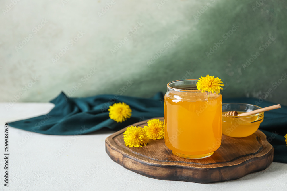 Jar and bowl with dandelion honey on white table