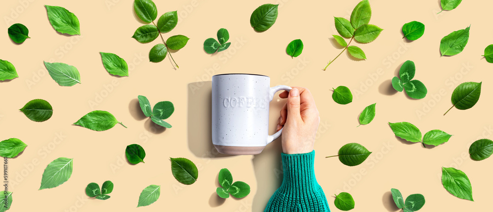 Person holding a mug with green leaves