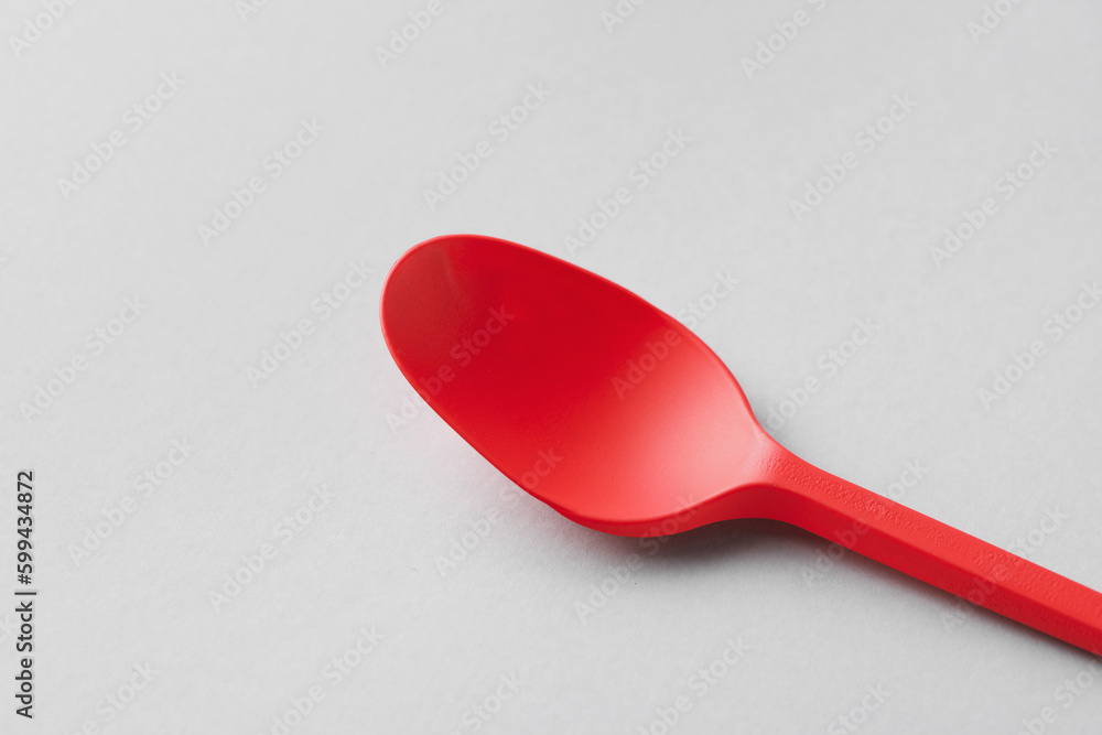 Red spoon on light background, closeup