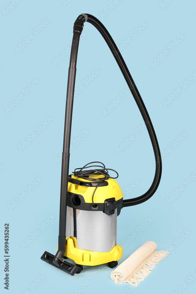 Vacuum cleaner with rolled carpet on blue background