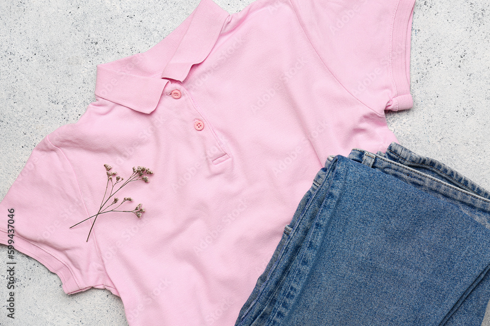 Stylish t-shirt, jeans and flowers on light background