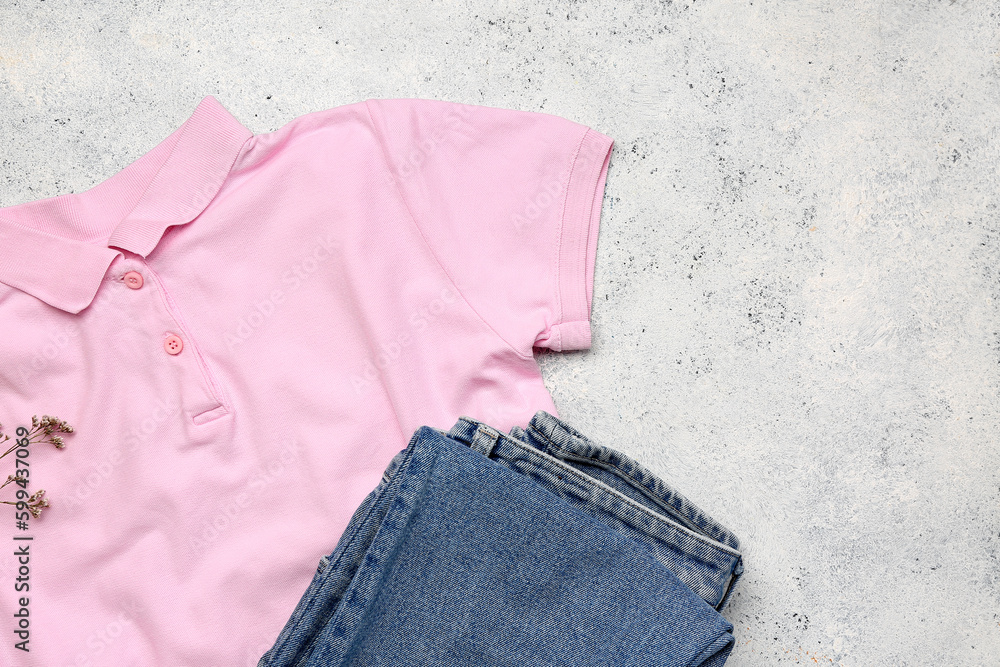 Stylish t-shirt, jeans and flowers on light background