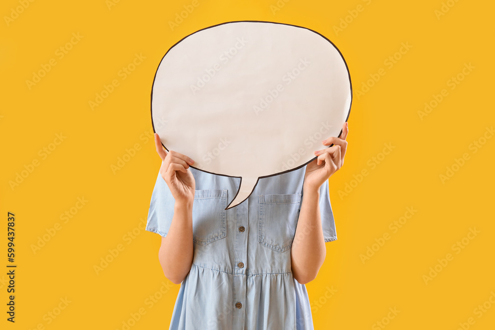 Young woman hiding face behind blank speech bubble on yellow background