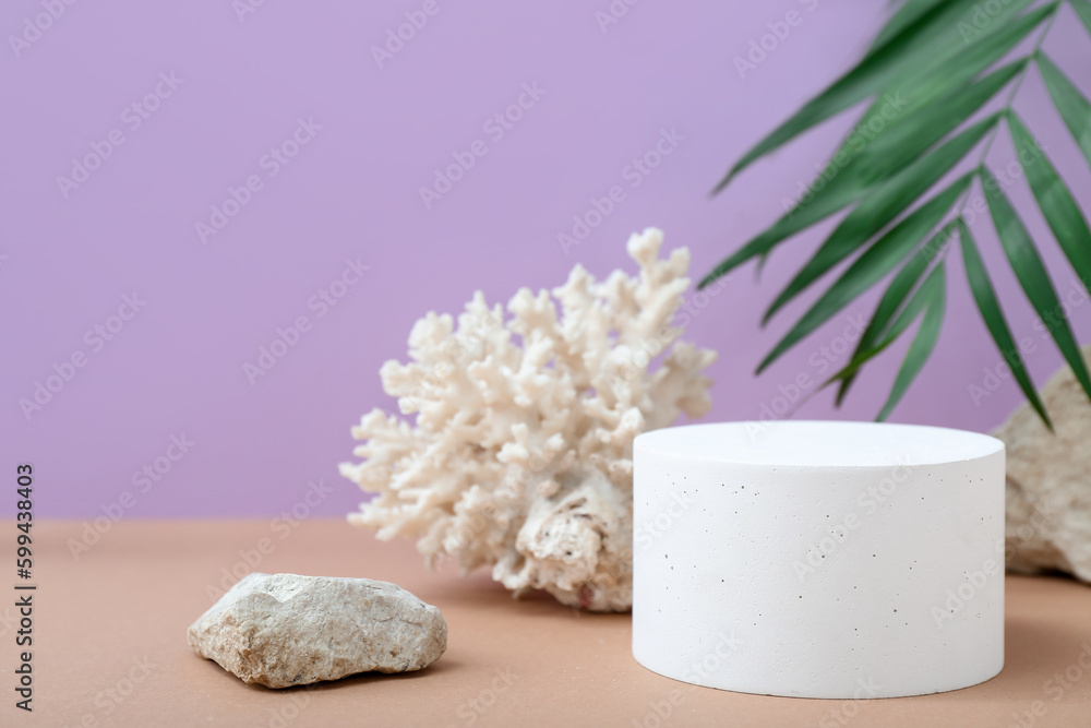 Decorative plaster podium, stones, coral and palm leaves on purple background