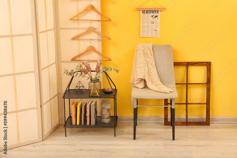 Interior of stylish room with shelving unit, chair and folding screen