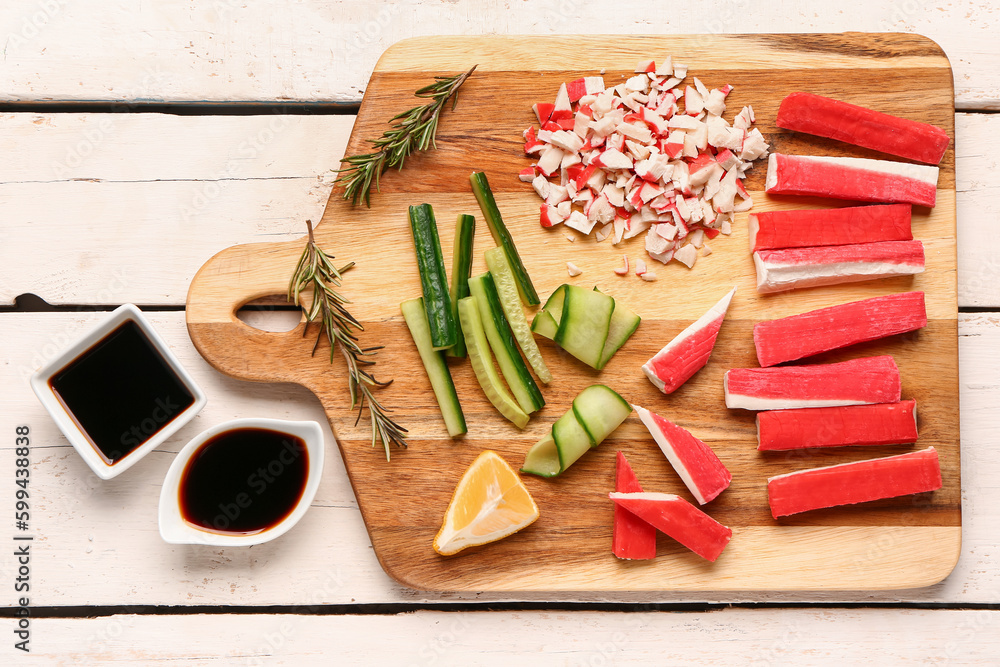 Board with tasty crab sticks and sauces on light wooden background