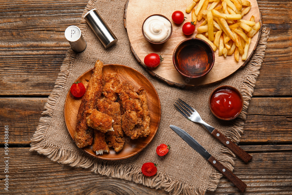 Plate of tasty fried codfish with sauces and french fries on wooden background