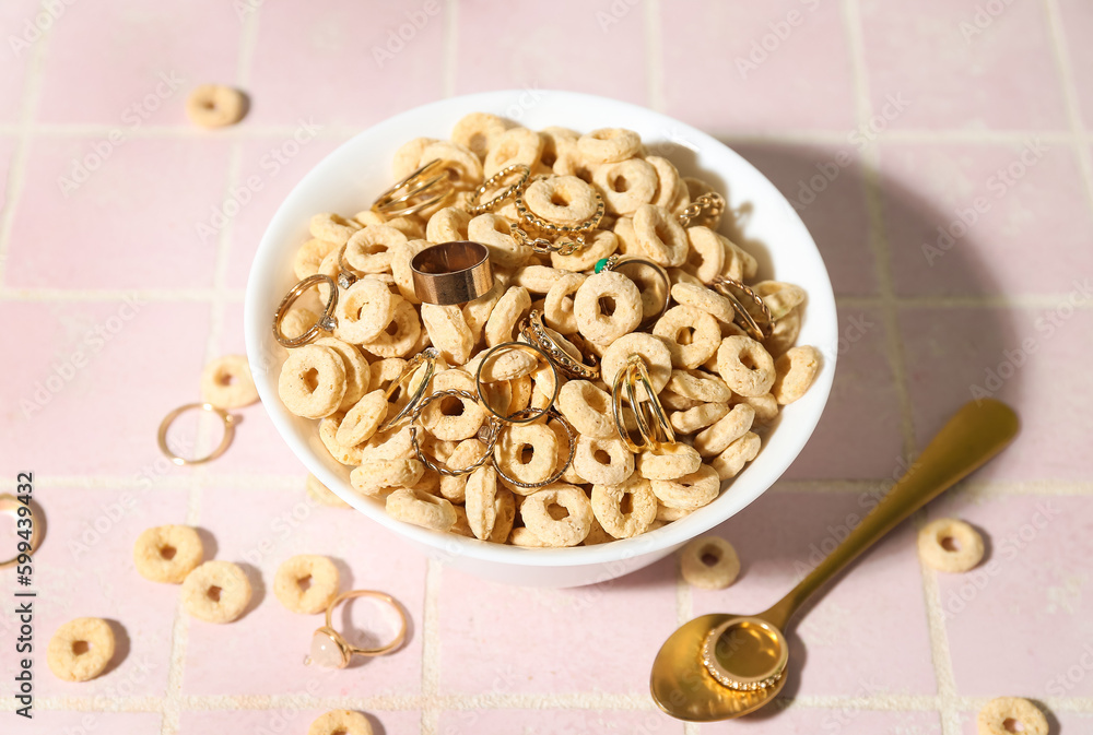 Bowl with cereal and golden rings on pink tile table