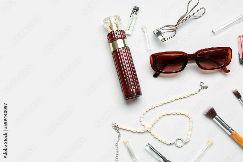 Sunglasses with perfume, jewelry and makeup brushes on white background