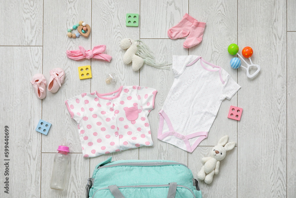 Stylish clothes and toys for baby on light wooden background