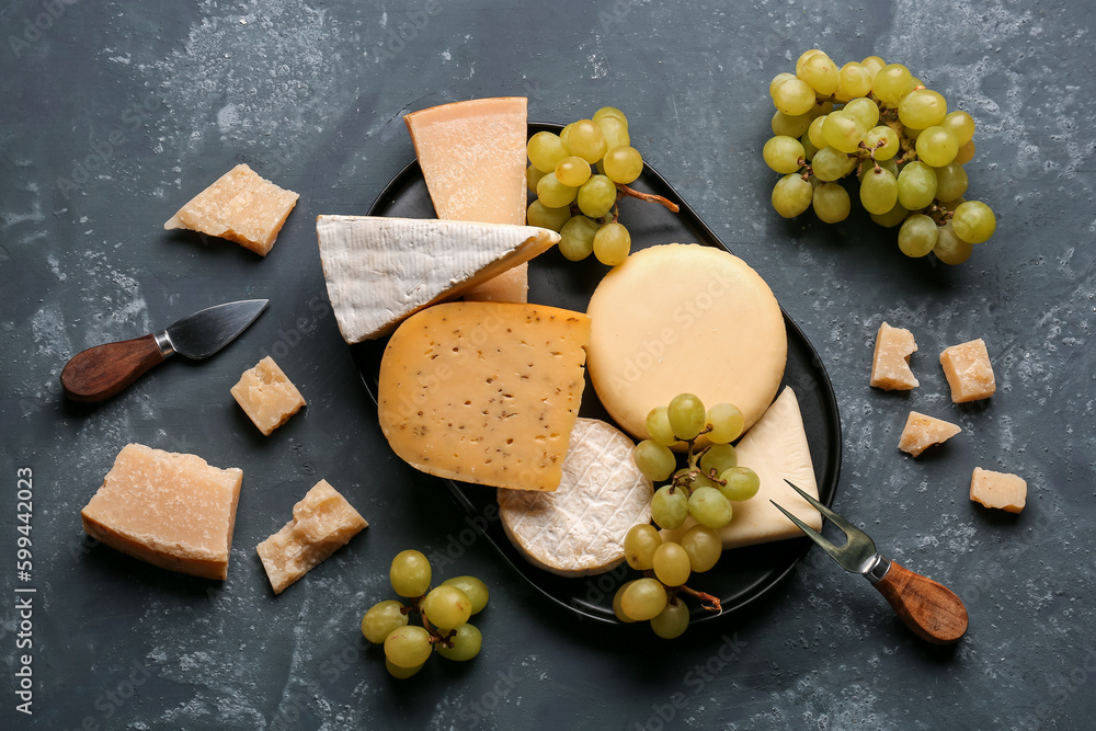 Different types of cheese with grapes on blue background