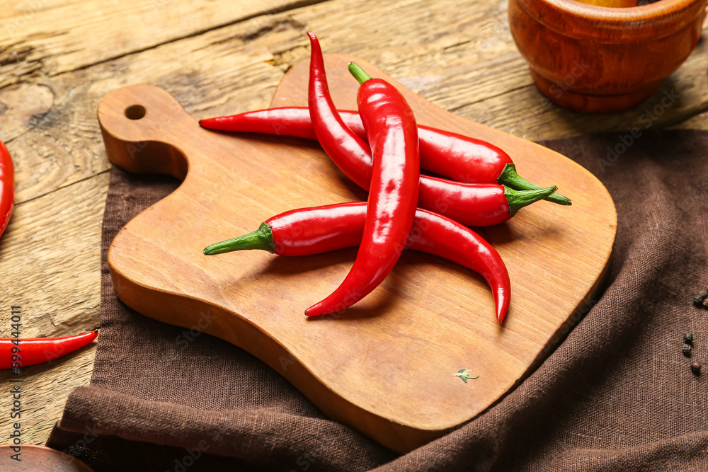 Board of fresh hot chili peppers on brown wooden background