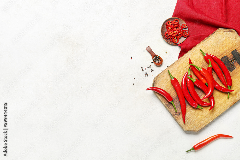 Board of fresh hot chili peppers with spices on white background