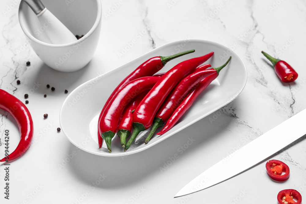 Plate with fresh chili peppers on white marble background