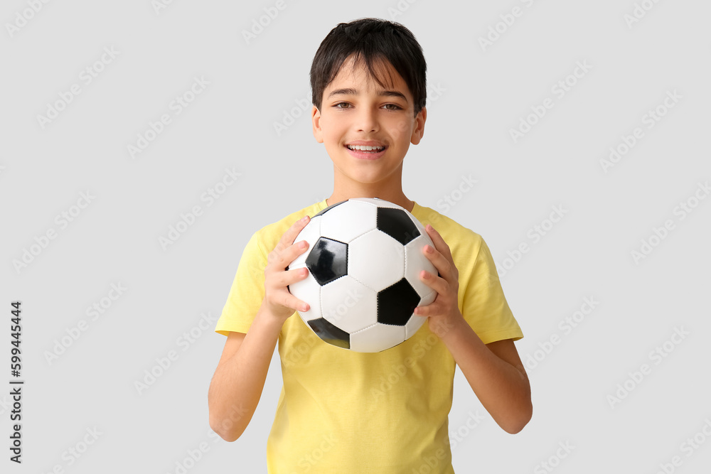 Little boy with soccer ball on grey background