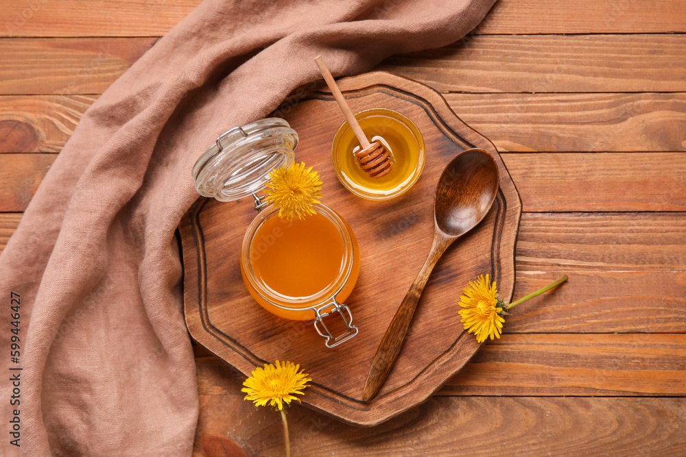 Jar and bowl with dandelion honey on wooden background