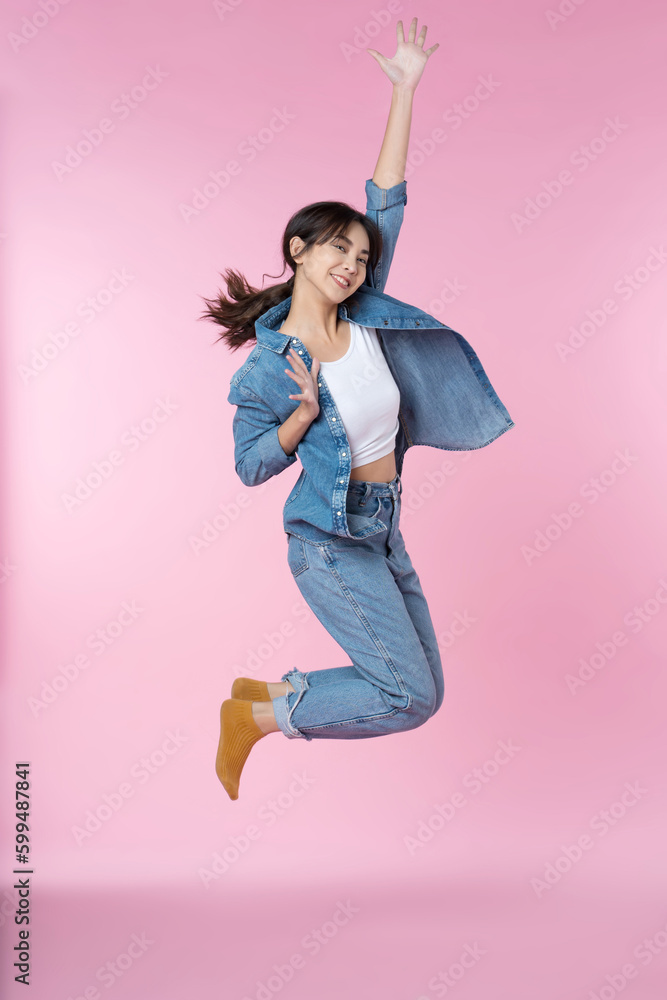 Elegant young Asian woman raises her arm and leg in a studio shot, expressing happiness and success 