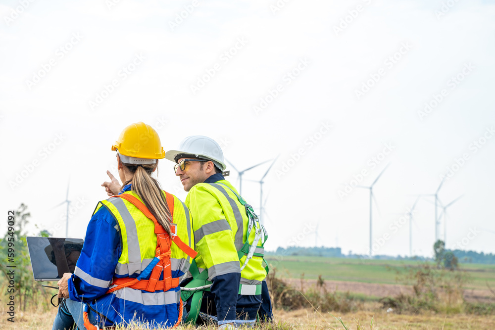 Engineer with technician are inspection work in wind turbine farms rotation to generate electricity 