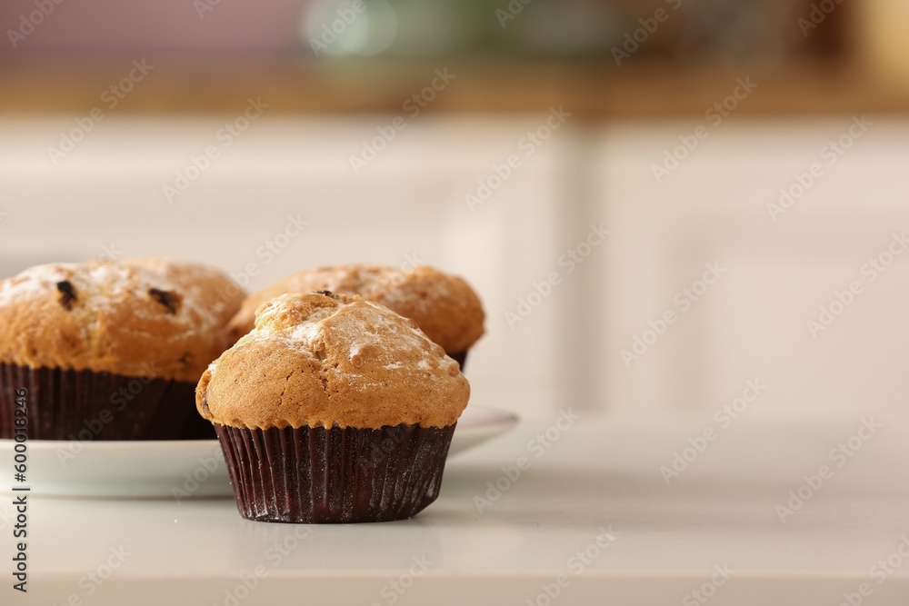 Plate with delicious muffins on table in kitchen