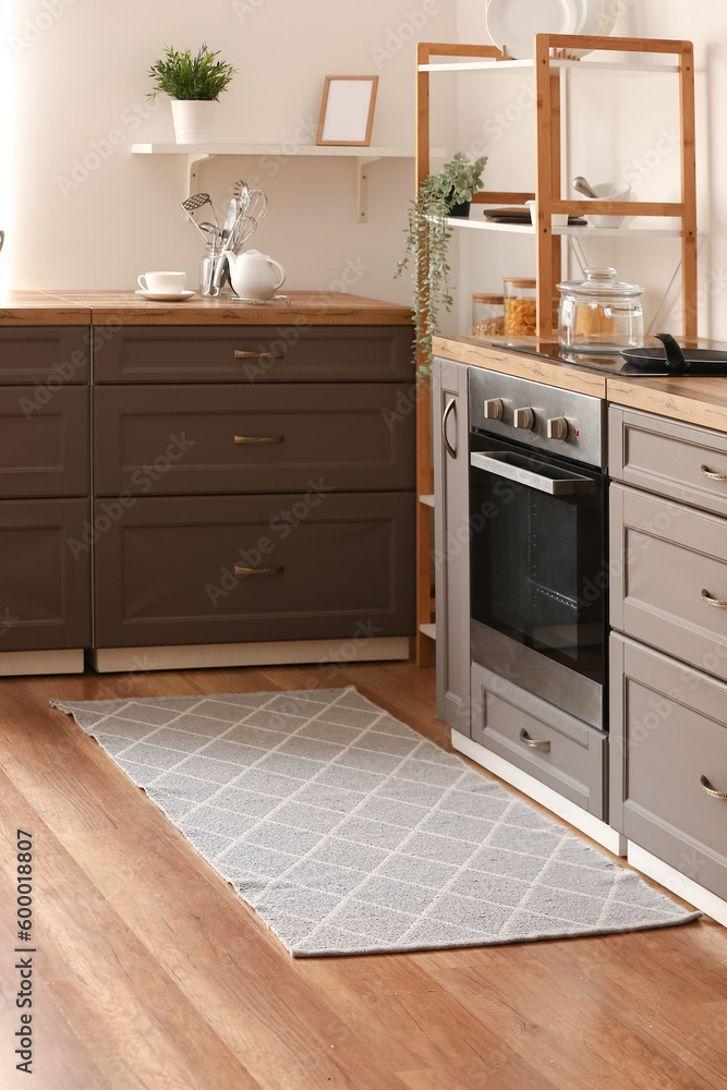 Stylish grey rug on floor in kitchen