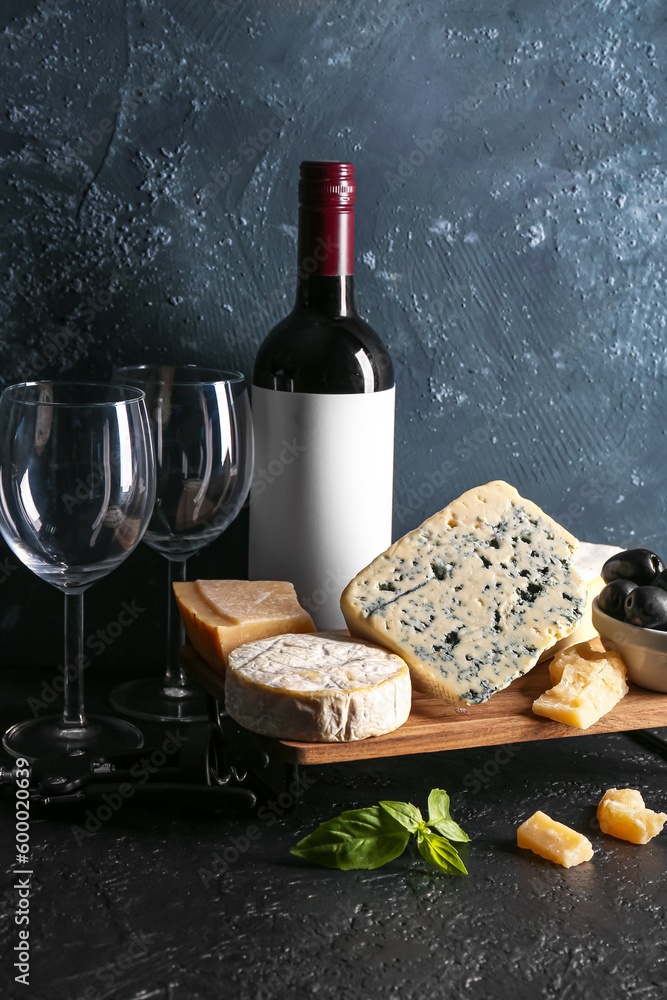 Different types of tasty cheese, glasses and bottle with wine on table