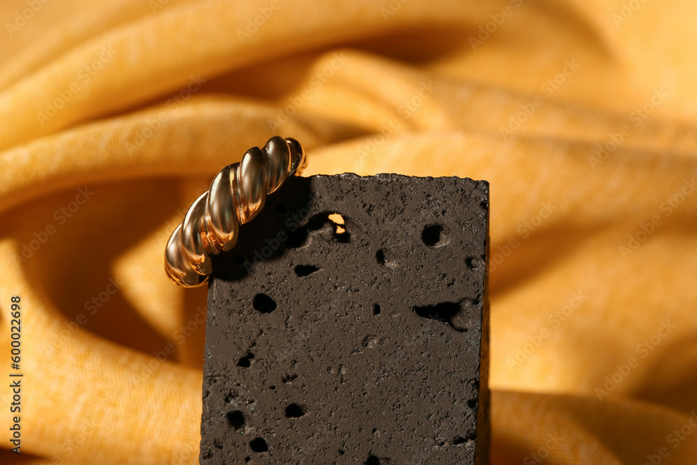 Decorative podium with beautiful ring on yellow fabric background