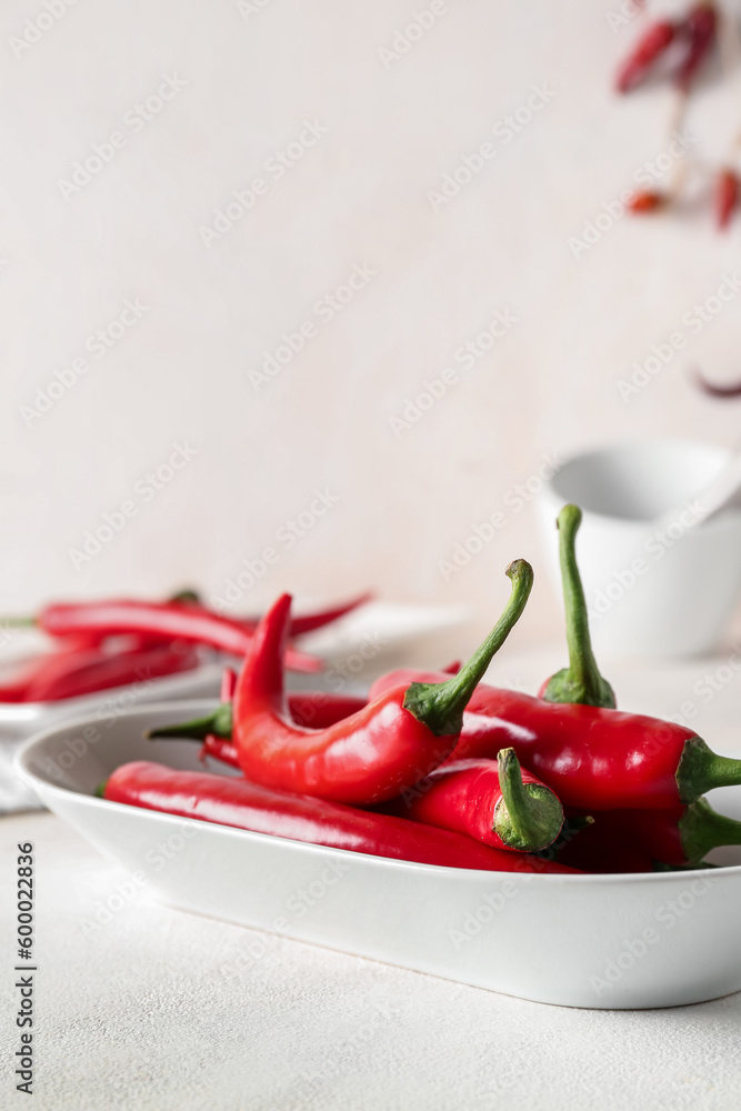 Plate of fresh chili peppers on light background