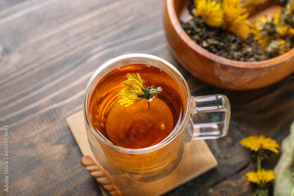 Bowl and glass cup of healthy dandelion tea on wooden background