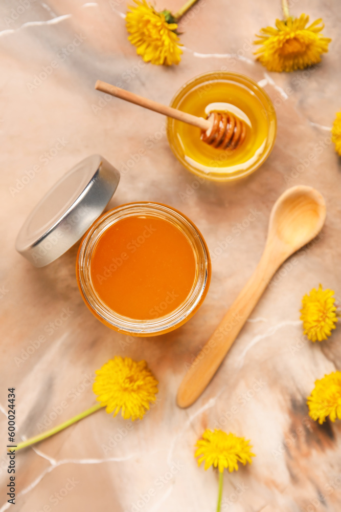 Jar and bowl with dandelion honey on marble background