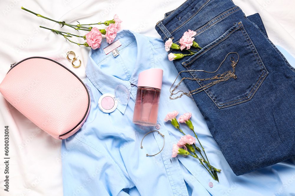 Composition with female accessories, cosmetics, clothes and carnation flowers on light fabric backgr