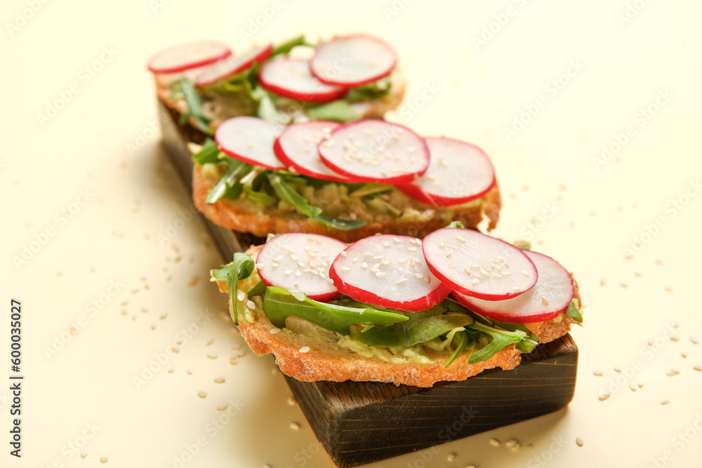 Board with delicious radish bruschettas on beige background