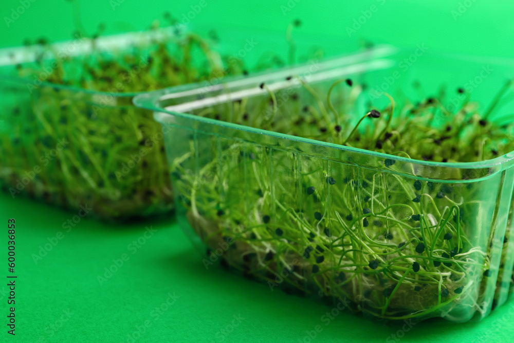 Plastic containers with fresh micro greens on color background, closeup