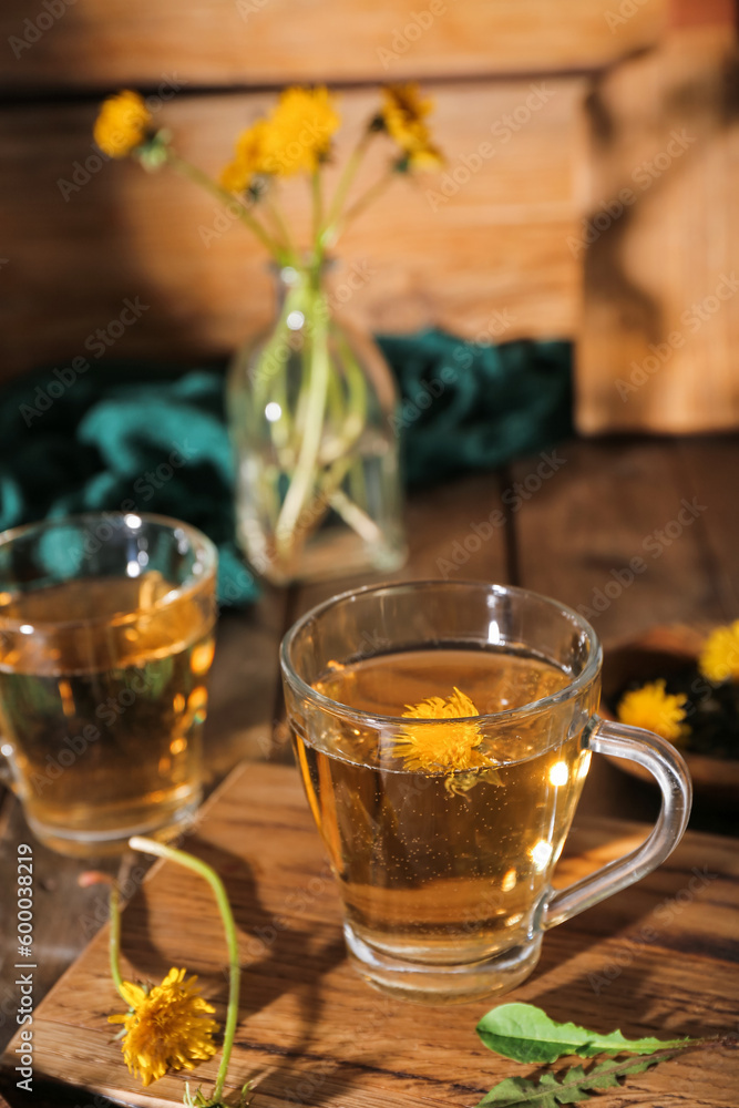 Board with glass cups of healthy dandelion tea on wooden table