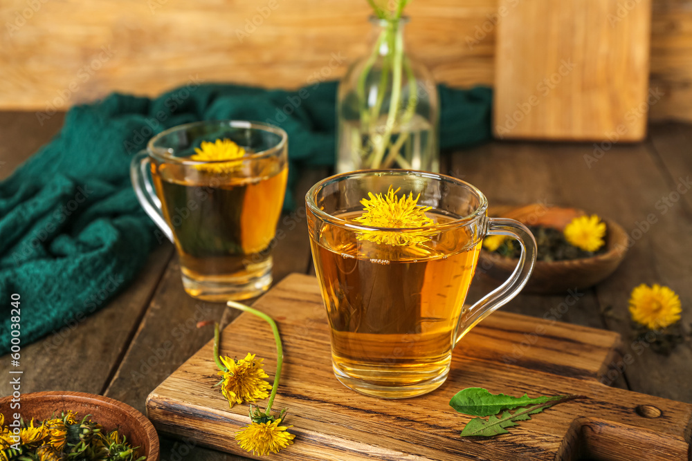 Board with glass cups of healthy dandelion tea on wooden table