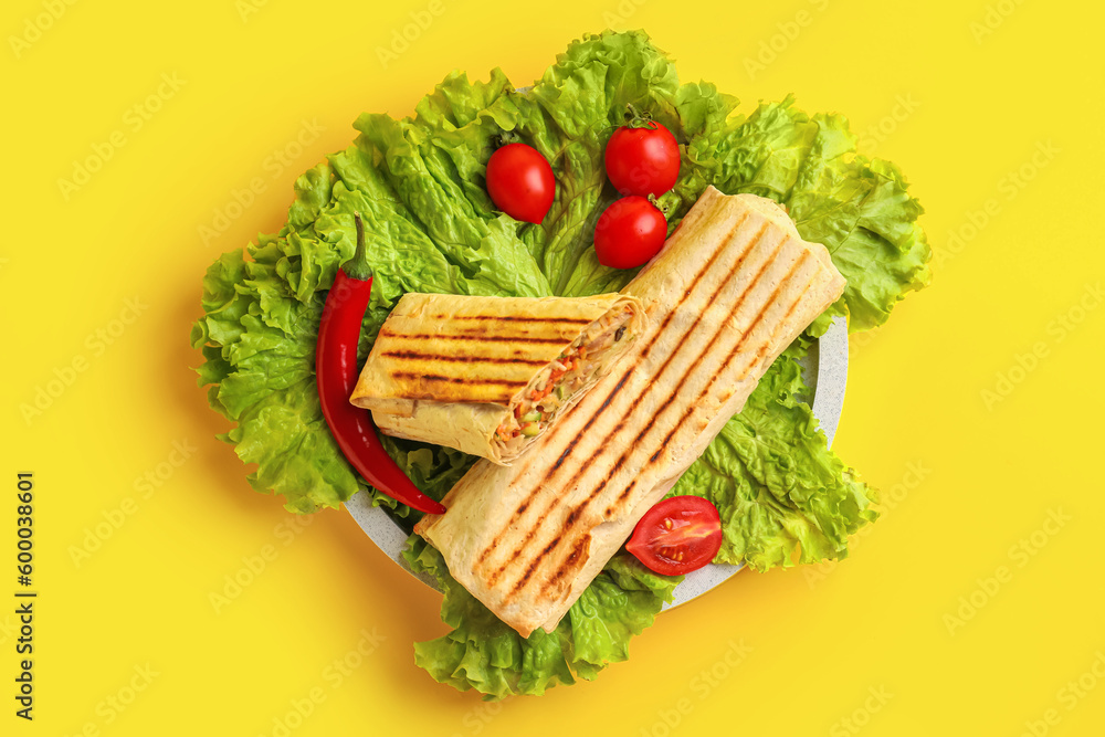 Plate of tasty shawarma with lettuce and tomatoes on yellow background