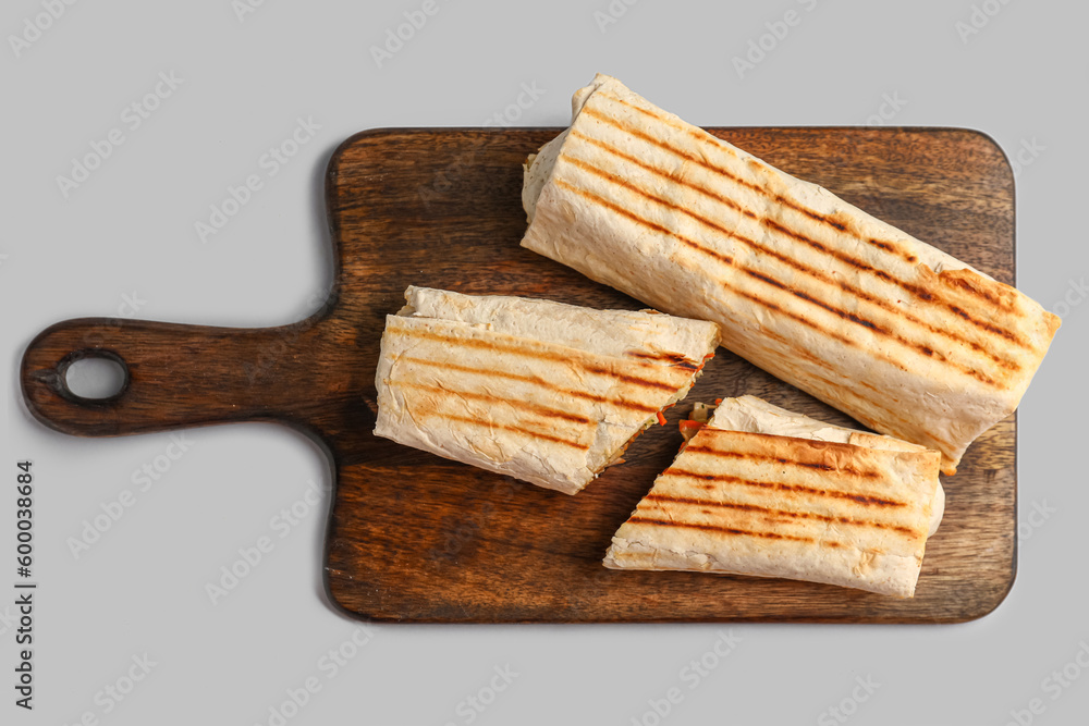 Board with tasty shawarma on grey background