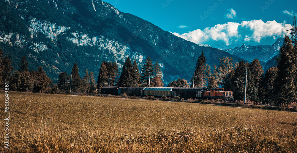 Train locomotive with freight on mountains background in autumn