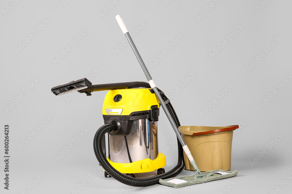 Vacuum cleaner with mop and bucket on grey background