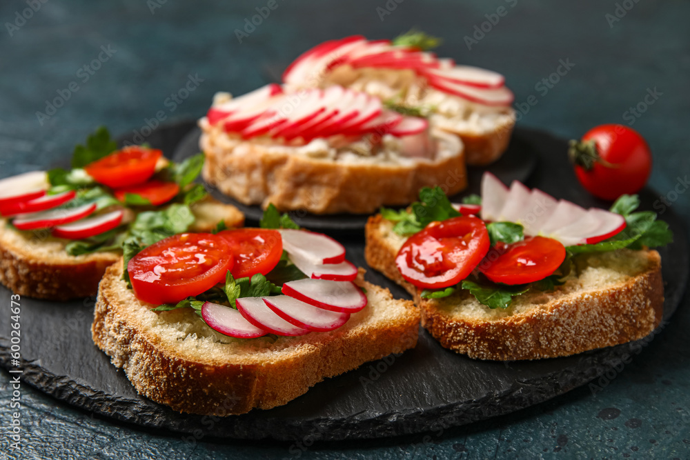 Board with delicious radish bruschettas on black table