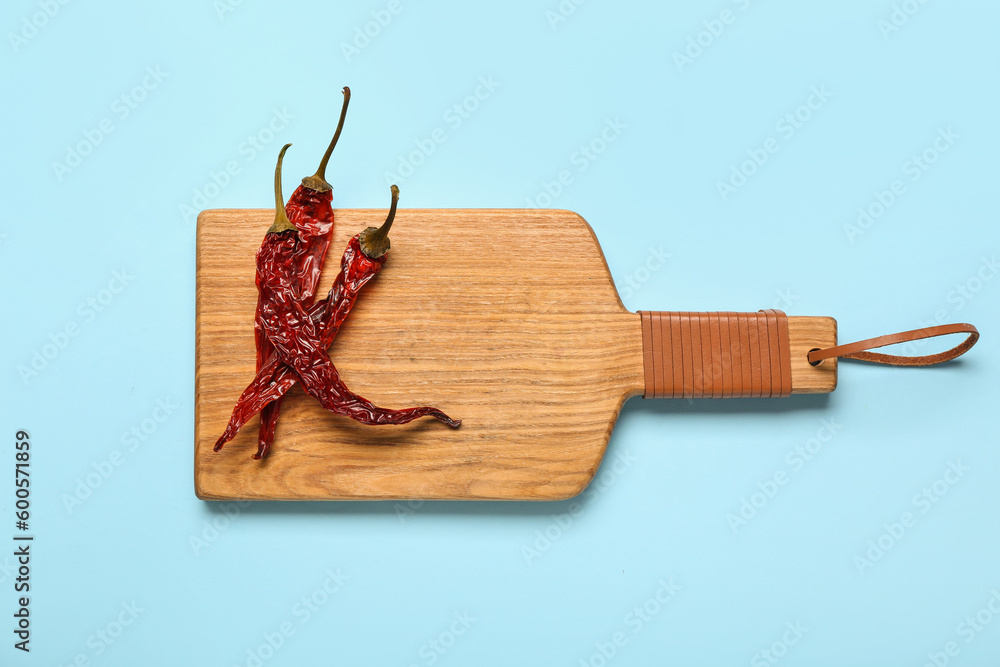 Board with dry hot chili peppers on blue background