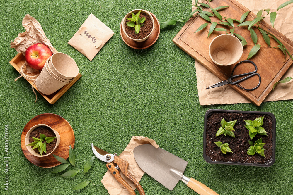 Frame made of seedlings, pack with seeds and gardening tools on green background