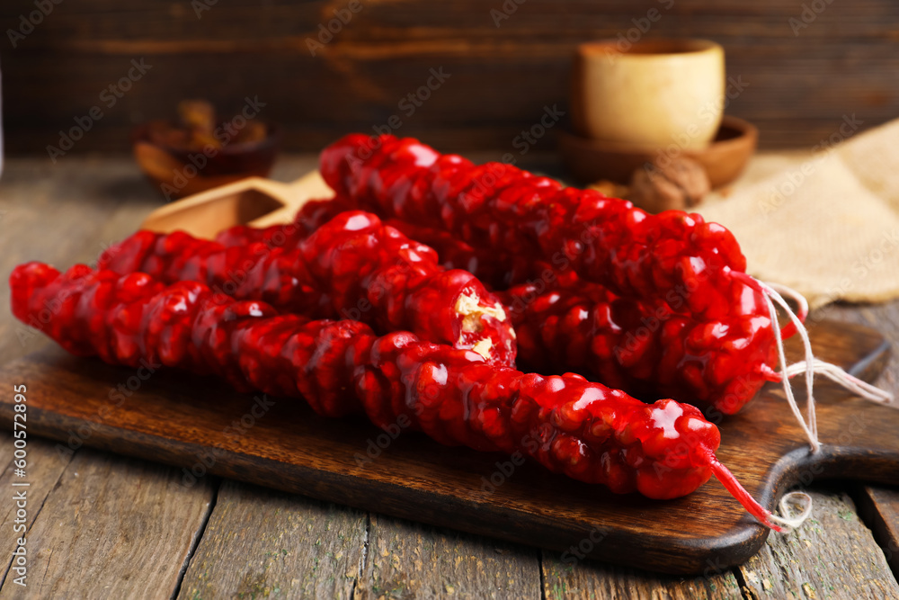 Board with tasty churchkhela on wooden background