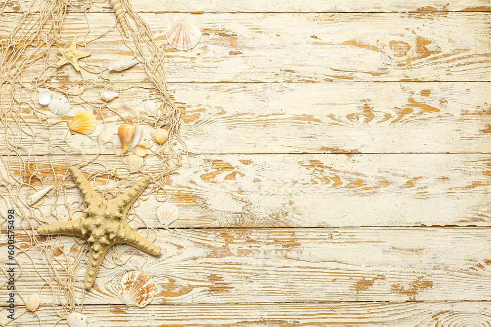 Beautiful starfish with seashells and net on light wooden background