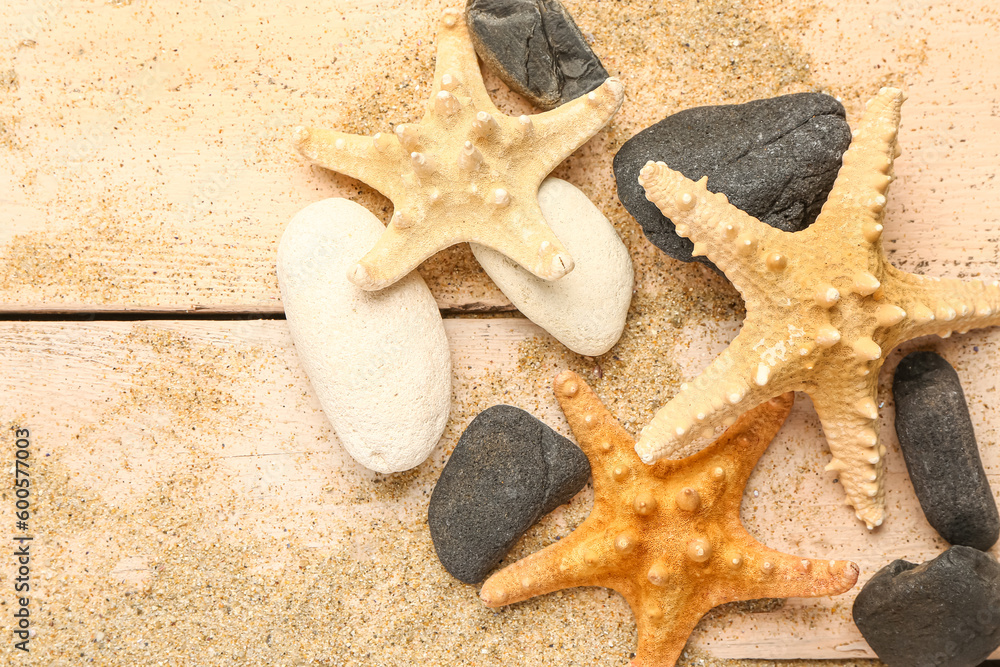 Sand with starfishes and shells on beige wooden background