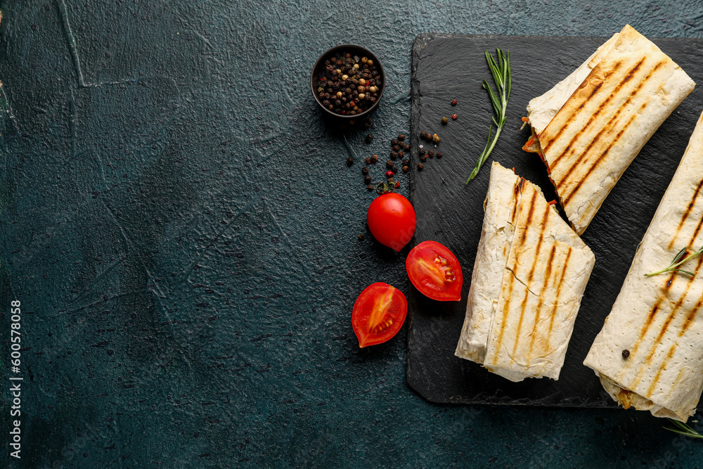 Board with tasty shawarma and tomatoes on dark background