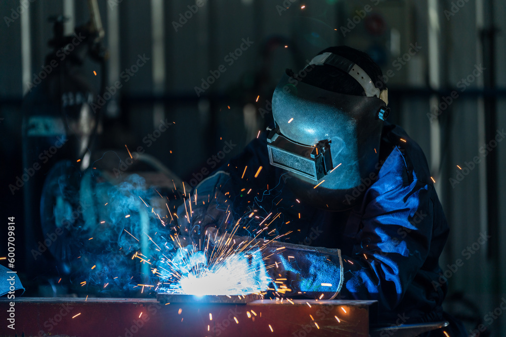 A workers wearing industrial uniforms and welded iron mask at steel welding plants, Industrial safet