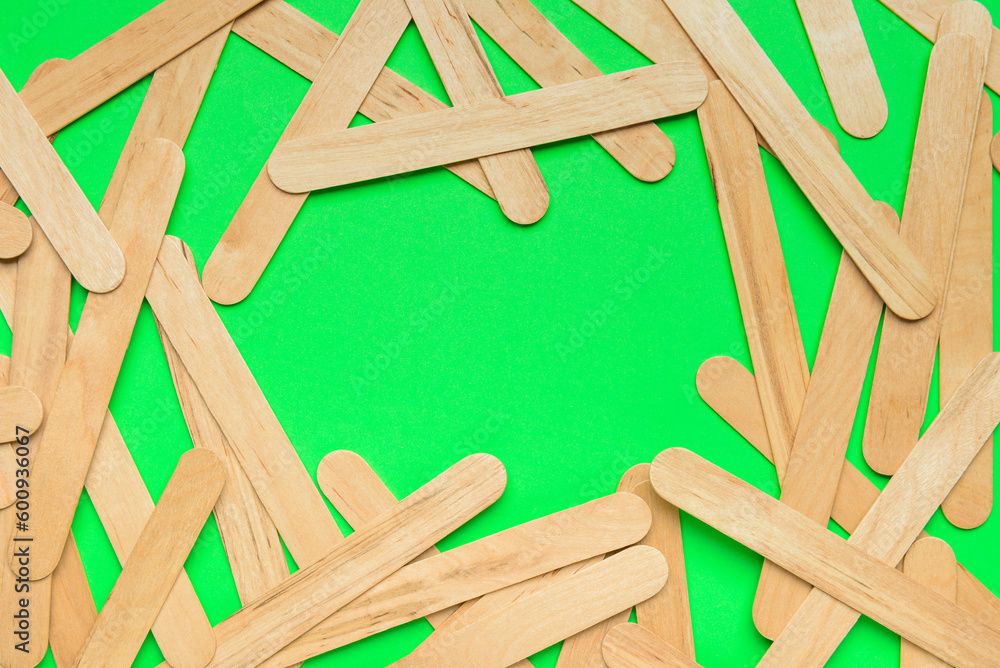 Frame made of ice cream sticks on green background